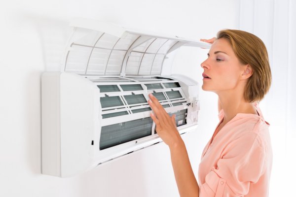 Kobieta otwierająca klimatyzator podczas serwisu